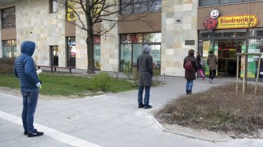 Varşova, Polonya. 3 Nisan 2020. Koronavirüs salgını sırasında kurallara uymak için marketin önünde sıra bekleyen insanlar.