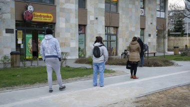 Varşova, Polonya. 3 Nisan 2020. Koronavirüs salgını sırasında kurallara uymak için marketin önünde sıra bekleyen insanlar.