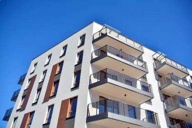 Mavi gökyüzü olan güneşli bir günde modern ve yeni bir apartman. Gündüz gözüyle çağdaş yerleşim yerinin dış tarafında..