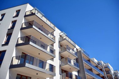 Mavi gökyüzü olan güneşli bir günde modern ve yeni bir apartman. Gündüz gözüyle çağdaş yerleşim yerinin dış tarafında..