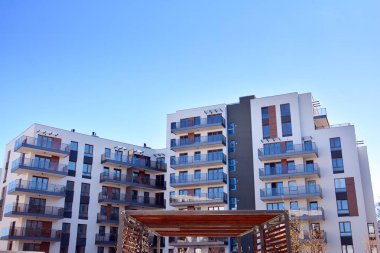 Mavi gökyüzü olan güneşli bir günde modern ve yeni bir apartman. Gündüz gözüyle çağdaş yerleşim yerinin dış tarafında..