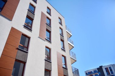 Mavi gökyüzü olan güneşli bir günde modern ve yeni bir apartman. Gündüz gözüyle çağdaş yerleşim yerinin dış tarafında..