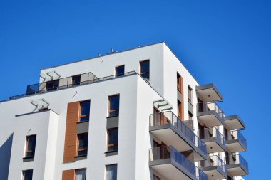 Mavi gökyüzü olan güneşli bir günde modern ve yeni bir apartman. Gündüz gözüyle çağdaş yerleşim yerinin dış tarafında..