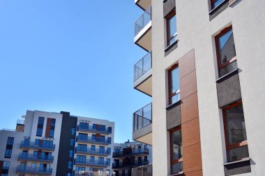 Mavi gökyüzü olan güneşli bir günde modern ve yeni bir apartman. Gündüz gözüyle çağdaş yerleşim yerinin dış tarafında..