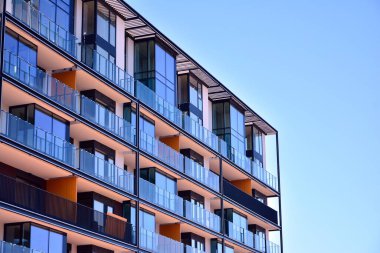 Mavi gökyüzü olan güneşli bir günde modern ve yeni bir apartman. Gündüz gözüyle çağdaş yerleşim yerinin dış tarafında..