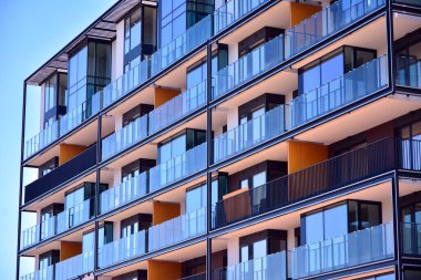 Mavi gökyüzü olan güneşli bir günde modern ve yeni bir apartman. Gündüz gözüyle çağdaş yerleşim yerinin dış tarafında..