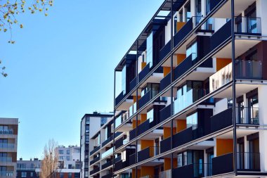 Mavi gökyüzü olan güneşli bir günde modern ve yeni bir apartman. Gündüz gözüyle çağdaş yerleşim yerinin dış tarafında..