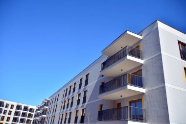 Mavi gökyüzü olan güneşli bir günde modern ve yeni bir apartman. Gündüz gözüyle çağdaş yerleşim yerinin dış tarafında..