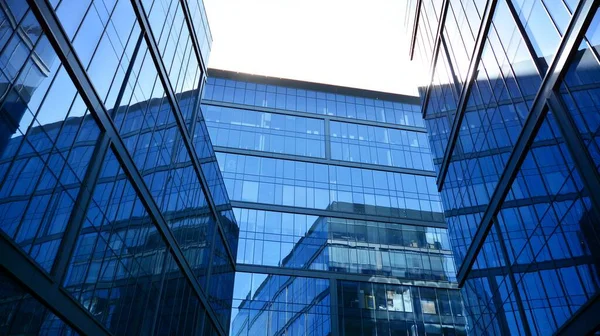 Blue curtain wall made of toned glass and steel constructions under blue sky. A fragment of a building.