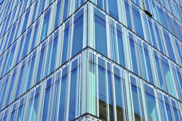 Blue curtain wall made of toned glass and steel constructions under blue sky. A fragment of a building.