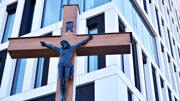 A cross with a figurine of Jesus against the background of the modern office building. The concept of cooperation between religion and business.