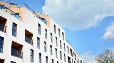 Gündüz gözüyle modern yerleşim yerinin dış tarafında. Mavi gökyüzü olan güneşli bir günde modern apartman binaları. Modern bir apartmanın cephesi