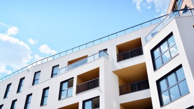 Gündüz gözüyle modern yerleşim yerinin dış tarafında. Mavi gökyüzü olan güneşli bir günde modern apartman binaları. Modern bir apartmanın cephesi