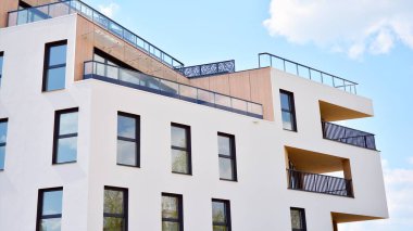 Gündüz gözüyle modern yerleşim yerinin dış tarafında. Mavi gökyüzü olan güneşli bir günde modern apartman binaları. Modern bir apartmanın cephesi