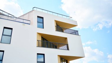 Gündüz gözüyle modern yerleşim yerinin dış tarafında. Mavi gökyüzü olan güneşli bir günde modern apartman binaları. Modern bir apartmanın cephesi