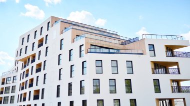 Gündüz gözüyle modern yerleşim yerinin dış tarafında. Mavi gökyüzü olan güneşli bir günde modern apartman binaları. Modern bir apartmanın cephesi