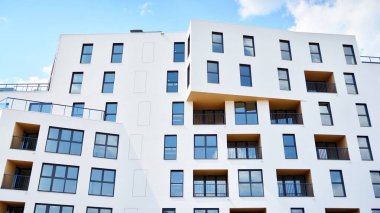 Gündüz gözüyle modern yerleşim yerinin dış tarafında. Mavi gökyüzü olan güneşli bir günde modern apartman binaları. Modern bir apartmanın cephesi