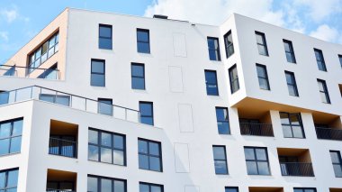 Gündüz gözüyle modern yerleşim yerinin dış tarafında. Mavi gökyüzü olan güneşli bir günde modern apartman binaları. Modern bir apartmanın cephesi