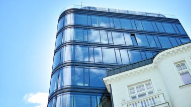 Dikey çizgileri ve yansıması olan modern ofis pencereleri. Gökyüzünü bulutlarla yansıtıyor ve gerçeküstü bir manzara yaratıyor..