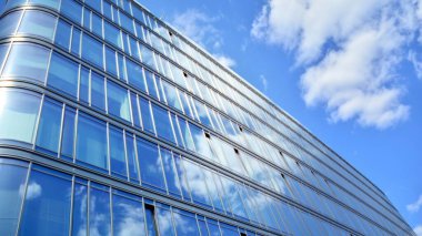 Dikey çizgileri ve yansıması olan modern ofis pencereleri. Gökyüzünü bulutlarla yansıtıyor ve gerçeküstü bir manzara yaratıyor..