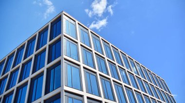 Dikey çizgileri ve yansıması olan modern ofis pencereleri. Gökyüzünü bulutlarla yansıtıyor ve gerçeküstü bir manzara yaratıyor..