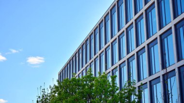 Dikey çizgileri ve yansıması olan modern ofis pencereleri. Gökyüzünü bulutlarla yansıtıyor ve gerçeküstü bir manzara yaratıyor..