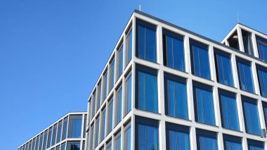 Dikey çizgileri ve yansıması olan modern ofis pencereleri. Gökyüzünü bulutlarla yansıtıyor ve gerçeküstü bir manzara yaratıyor..