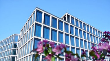 Dikey çizgileri ve yansıması olan modern ofis pencereleri. Gökyüzünü bulutlarla yansıtıyor ve gerçeküstü bir manzara yaratıyor..