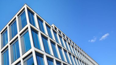 Dikey çizgileri ve yansıması olan modern ofis pencereleri. Gökyüzünü bulutlarla yansıtıyor ve gerçeküstü bir manzara yaratıyor..