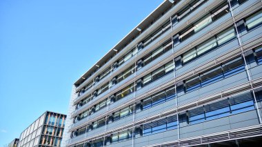 Dikey çizgileri ve yansıması olan modern ofis pencereleri. Gökyüzünü bulutlarla yansıtıyor ve gerçeküstü bir manzara yaratıyor..