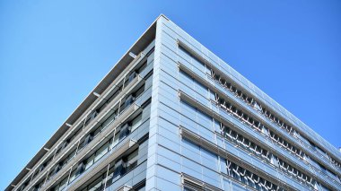 Dikey çizgileri ve yansıması olan modern ofis pencereleri. Gökyüzünü bulutlarla yansıtıyor ve gerçeküstü bir manzara yaratıyor..