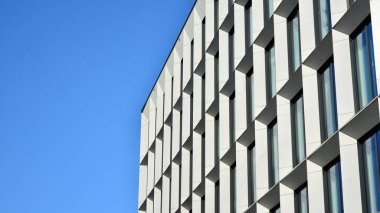 Dikey çizgileri ve yansıması olan modern ofis pencereleri. Gökyüzünü bulutlarla yansıtıyor ve gerçeküstü bir manzara yaratıyor..