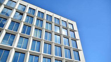 Dikey çizgileri ve yansıması olan modern ofis pencereleri. Gökyüzünü bulutlarla yansıtıyor ve gerçeküstü bir manzara yaratıyor..