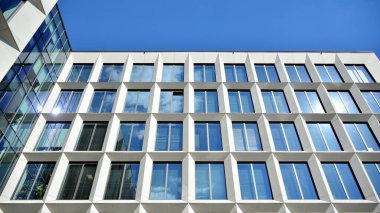 Dikey çizgileri ve yansıması olan modern ofis pencereleri. Gökyüzünü bulutlarla yansıtıyor ve gerçeküstü bir manzara yaratıyor..