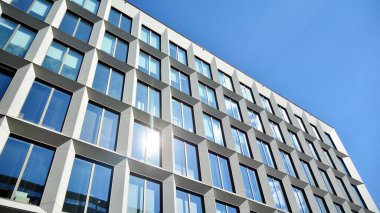 Dikey çizgileri ve yansıması olan modern ofis pencereleri. Gökyüzünü bulutlarla yansıtıyor ve gerçeküstü bir manzara yaratıyor..