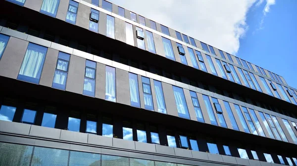 Dikey çizgileri ve yansıması olan modern ofis pencereleri. Gökyüzünü bulutlarla yansıtıyor ve gerçeküstü bir manzara yaratıyor..