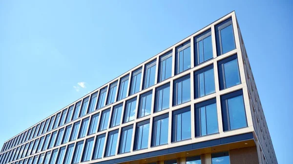 Dikey çizgileri ve yansıması olan modern ofis pencereleri. Gökyüzünü bulutlarla yansıtıyor ve gerçeküstü bir manzara yaratıyor..