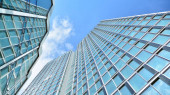 Strukturální skleněná stěna odrážející modré nebe. Abstraktní fragment moderní architektury. Pohled na moderní skleněný mrakodrap, moderní administrativní budovu. Moderní kancelářská fasáda fragment s modrým sklem.