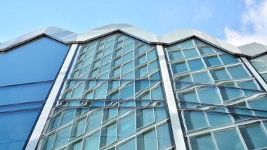 Yapısal cam duvar mavi gökyüzünü yansıtıyor. Soyut modern mimari parçası. Modern cam gökdelen manzarası, modern ofis binası. Modern ofis cephesi mavi camlı.