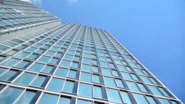 Yapısal cam duvar mavi gökyüzünü yansıtıyor. Soyut modern mimari parçası. Modern cam gökdelen manzarası, modern ofis binası. Modern ofis cephesi mavi camlı.