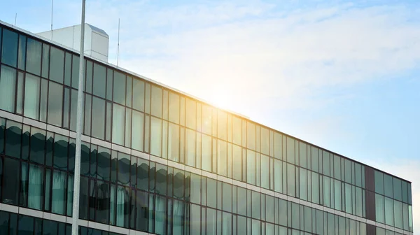 Glass building with blue sky background. Modern office building detail, glass surface clouds reflected in windows of modern office building.