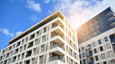 Mavi gökyüzü olan güneşli bir günde modern apartman binaları. Modern bir apartmanın ön cephesi. Güneş ışığıyla cam yüzey.