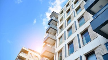 Mavi gökyüzü olan güneşli bir günde modern apartman binaları. Modern bir apartmanın ön cephesi. Güneş ışığıyla cam yüzey.
