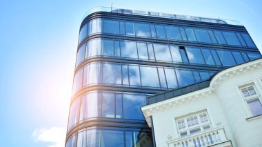 Şehirde günışığı olan modern bir bina. Gün ışığında bir ofis binasının cam duvarı. Ofis penceresi gün doğumu, yansıma ve perspektifle kapanıyor.