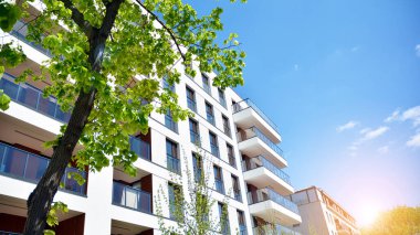 Mavi gökyüzü olan güneşli bir günde modern apartman binaları. Modern bir apartmanın ön cephesi. Güneş ışığıyla cam yüzey.