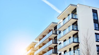 Mavi gökyüzü olan güneşli bir günde modern apartman binaları. Modern bir apartmanın ön cephesi. Güneş ışığıyla cam yüzey.