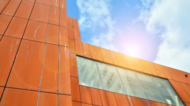 Şehirde günışığı olan modern bir bina. Gün ışığında bir ofis binasının cam duvarı. Ofis penceresi gün doğumu, yansıma ve perspektifle kapanıyor.