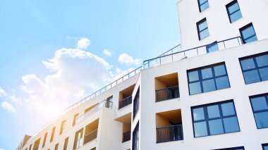 Mavi gökyüzü olan güneşli bir günde modern apartman binaları. Modern bir apartmanın ön cephesi. Güneş ışığıyla cam yüzey.