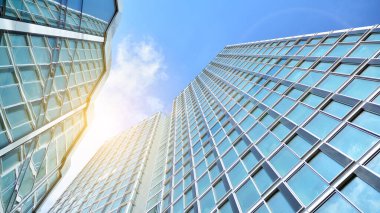 Şehirde günışığı olan modern bir bina. Gün ışığında bir ofis binasının cam duvarı. Ofis penceresi gün doğumu, yansıma ve perspektifle kapanıyor.