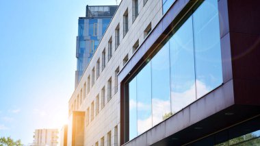 Mavi gökyüzü olan güneşli bir günde modern apartman binaları. Modern bir apartmanın ön cephesi. Güneş ışığıyla cam yüzey.